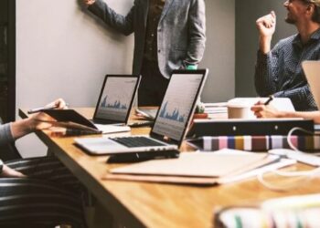 Personas reunidas en mesa con portátiles