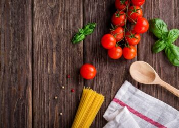 Pasta, tomate y albahaca fresca en mesa de madera